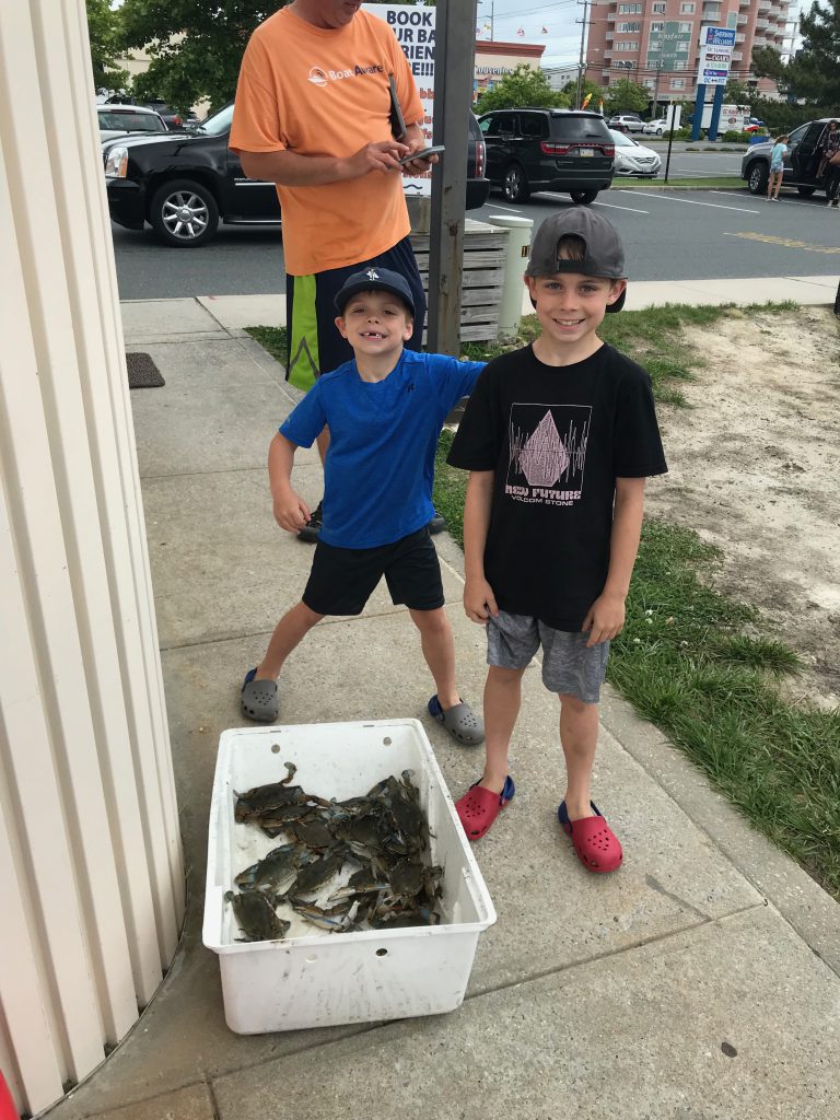 Two boys showing crabs they caught on crabbing cruise